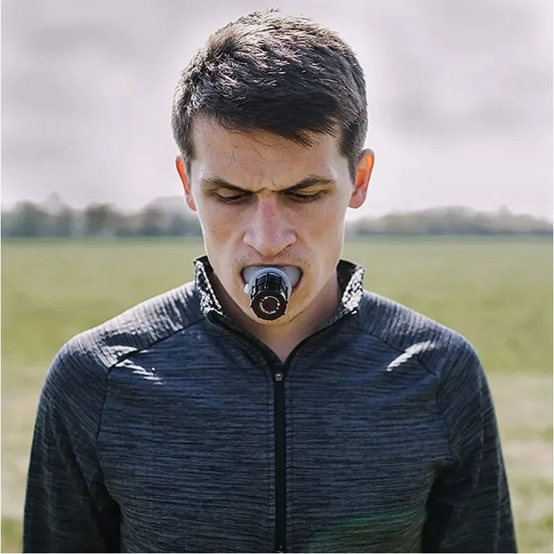 Male athlete using a sports breathing trainer mouthpiece outdoors to improve endurance and lung control