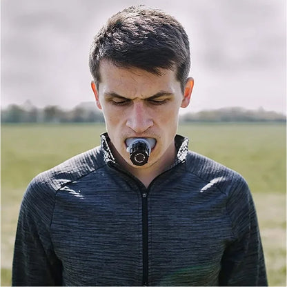 Male athlete using a sports breathing trainer mouthpiece outdoors to improve endurance and lung control