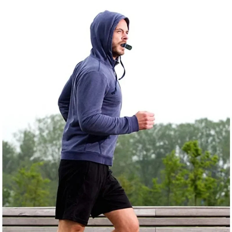 Man jogging outdoors in hoodie using HealthyRealLife sports breathing trainer mouth device to improve running endurance