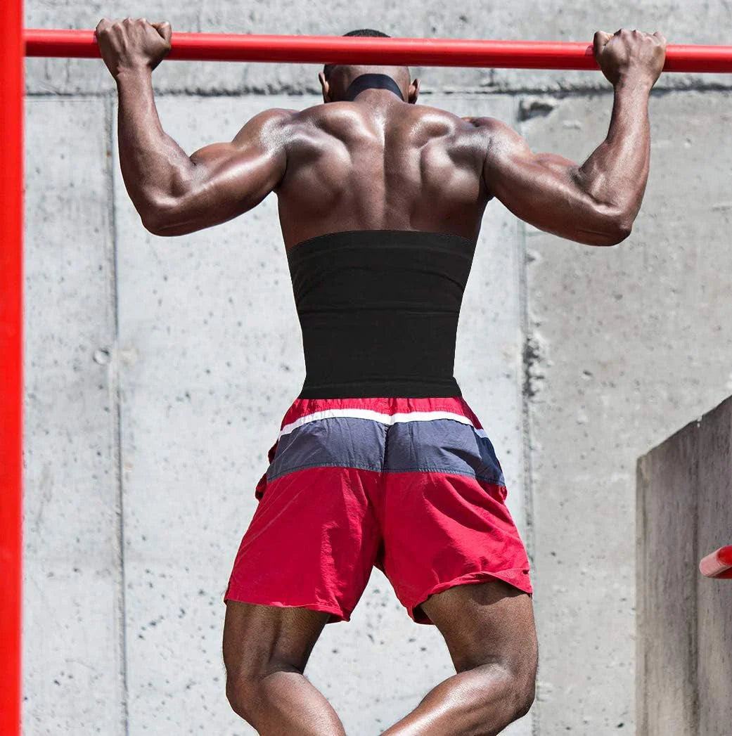Muscular man doing pull ups outdoors wearing a black sauna waist trimmer belt for men and red shorts