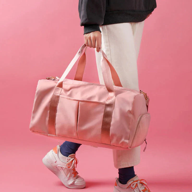 HealthyRealLife pink waterproof fitness duffel bag with dual handles and side pocket carried by person wearing sneakers