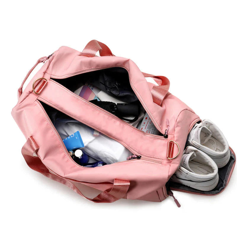Pink waterproof fitness duffel bag open showing side shoe compartment clothes water bottle and toiletries